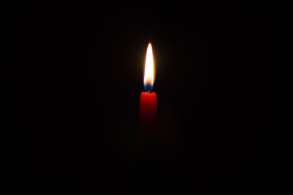 Kynttilän liekki, joka palaa pimeässä. 